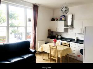 伦敦Lovely Flat in Central London的客厅配有桌子和黑色沙发