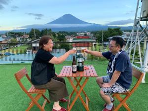 富士河口湖赤石旅馆的坐在桌子上的两个人,拿着一瓶葡萄酒