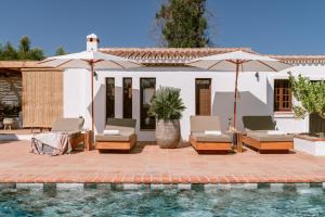 蒙达San Roque Suites de Monda的房屋旁的游泳池配有椅子和遮阳伞