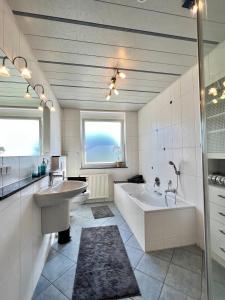 OberteuringenCharmantes Landhaus的一间带两个盥洗盆、浴缸和窗户的浴室