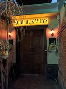 沙努尔Kubu Di-Kayla's的上方标有标志的餐厅的门