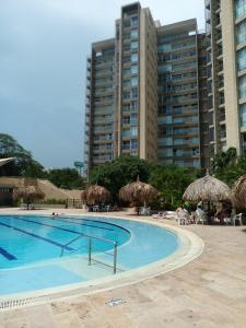 圣玛尔塔Beautiful Beach Apartment in Zazue的一个带稻草遮阳伞和椅子的游泳池以及建筑