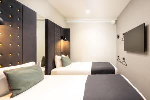伦敦伦敦国王十字 - 圣潘克拉斯A点酒店 的酒店客房设有两张床和一台平面电视。