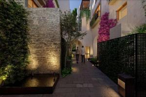 圣米格尔-德阿连德Le Cottage San Miguel de Allende, Modern Luxury in Centro with Pool & Jacuzzi的两个人在大楼的走道上走