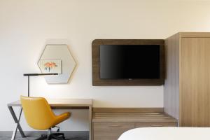 托莱多北托莱多智选假日酒店的一间卧室配有书桌、电视和黄椅。