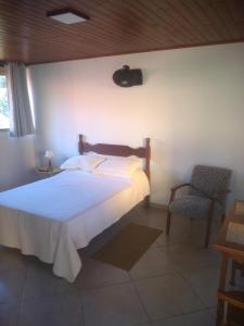 圣佩德罗塞拉Chalés da Serra的卧室配有白色的床和椅子