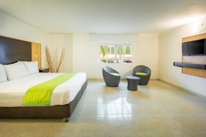 圣安德烈斯Hotel Americas San Andres Islas Colombia的酒店客房,配有一张床和两把椅子