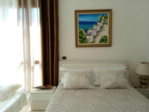 伏罗拉Guest room near historical center的卧室配有一张白色床,墙上挂着一幅画