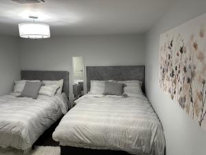 布兰普顿Luxurious and modern one bedroom basement suite.的一间卧室设有两张床,墙上挂着一幅画
