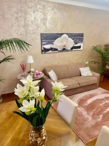 米兰Appartamento Benaco a Milano - Fondazione Prada的客厅配有沙发,花瓶里鲜花
