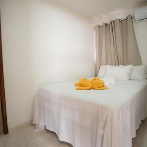 马拉戈日Pousada Villa Costeira的一张白色的床,上面有两条黄色的毛巾