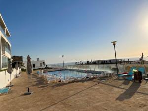 塞拉Appart de Luxe front de mer Prestigia Plage des Nations的海滩旁的游泳池,配有椅子
