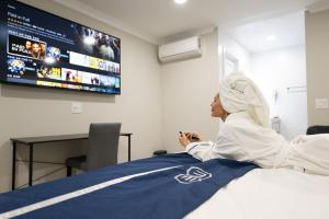 阿罕布拉Omeo Suites的躺在床上看电视的女人