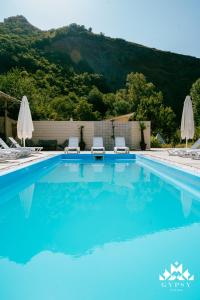 AsuretʼiGipsy Village Park Hotel的蓝色游泳池,配有两把椅子和遮阳伞