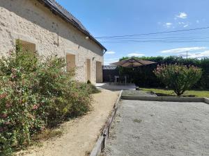 CorzéGîte de charme rénové avec jardin clos, baignoire balnéo et proche d'Angers - FR-1-622-27的一座石头建筑,设有庭院和遮阳伞