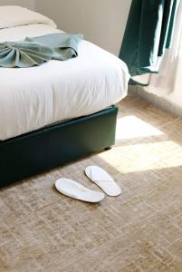 麦地那فندق زوايا الماسية فرع الحمراء的睡床旁边的地板上一对白色的拖鞋