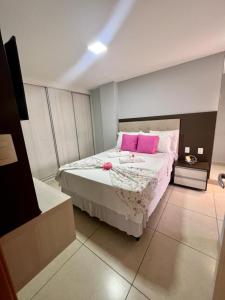 卡贝德卢Apartamento a beira-mar com piscina的卧室配有一张带粉红色枕头的大床