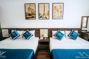 宁平Milan Hotel Ninh Bình的配有两张床铺的蓝色和白色枕头