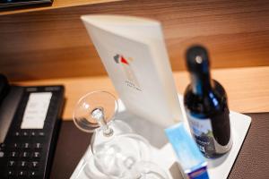 考夫博伊伦埃姆托姆酒店的遥控器旁边的桌子上放一瓶葡萄酒