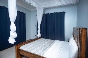 坎帕拉PearlCrest townhomes的一间卧室配有一张带蓝色墙壁和黑色窗帘的床。