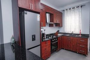 坎帕拉PearlCrest townhomes的厨房配有白色冰箱和木制橱柜。