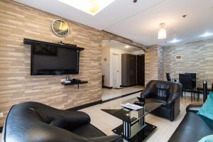 马尼拉Pacific Bay Grand Suites的客厅配有皮革家具和平面电视