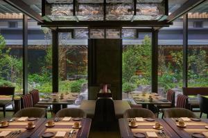 京都Dusit Thani Kyoto的餐厅设有桌椅和大窗户。