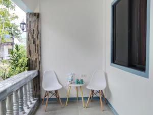 马拉帕斯加ELEN INN - Malapascua Island Air-conditioned Room2的阳台配有两把椅子和一张桌子,阳台设有窗户