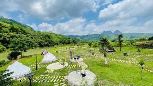 和平Caofong Glamping Village Hoà Bình的享有带帐篷和山脉的田野的空中景致