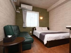 石垣岛ホテルアビアンパナ石垣島的酒店客房,配有一张床和一把绿色椅子
