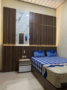 KemiriDavid Guesthouse by XNR的一间卧室配有一张带蓝白色毯子的床