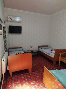 布哈拉Masturabonu Ravshan的客房设有两张床和一台墙上的电视。
