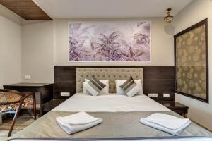 莫尔吉姆Skon Morjim Beach Resort by Orion Hotels的卧室配有一张大床,墙上挂有绘画作品