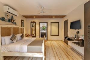 莫尔吉姆Skon Morjim Beach Resort by Orion Hotels的一间卧室配有一张大床和一台平面电视