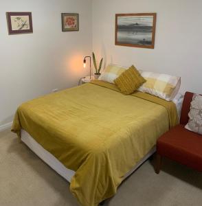 亚斯Private Room with Ensuite的一间卧室配有一张带黄色床罩和椅子的床