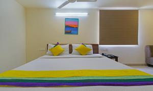 维杰亚瓦达Itsy By Treebo - N Square的一间卧室配有一张大床,提供黄色和色彩缤纷的枕头