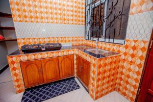 达累斯萨拉姆Niwa Apartments的橙色的厨房设有水槽和镜子