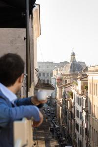 罗马Condominio Monti Boutique Hotel的把一杯咖啡藏在阳台上的人