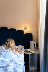 罗马Condominio Monti Boutique Hotel的躺在床上读书的女人