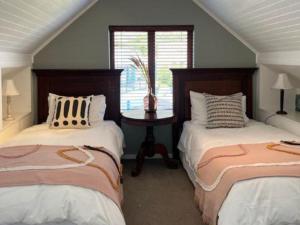 Clovelly邓韦根小屋旅馆的一间卧室设有两张床和一张桌子及窗户