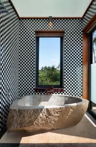 日惹Garrya Bianti Yogyakarta的窗户客房内的大石头浴缸