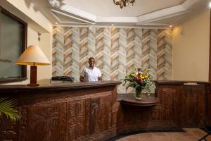 蒙巴萨森特林城堡皇家酒店的站在酒店大堂酒吧的男人