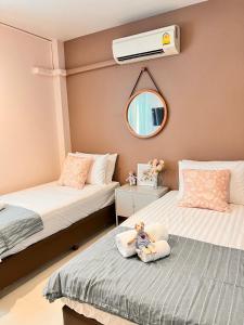 北碧Por poshtel Kanchanaburi的一间卧室配有两张床,枕头上有一个娃娃