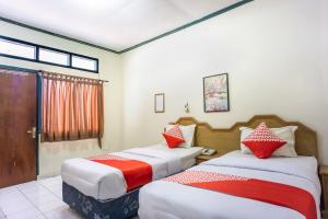 LhokseumaweOYO 1636 Wisma Kuta Karang的一间卧室配有两张带红白色枕头的床