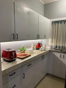 上哈特The Cozy Hutt Home的厨房配有白色橱柜和台面上的红色用具
