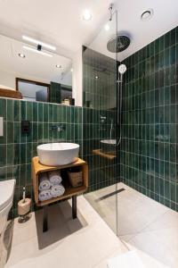 维尔茨堡The Barthels Boutique Hotel的绿色瓷砖浴室设有水槽和淋浴