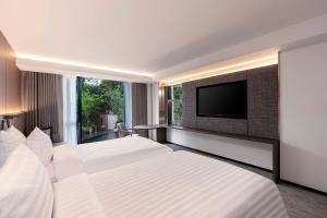 曼谷Gardina Asoke Hotel & Residence - SHA Certified的一间卧室配有两张床和一台平面电视