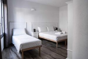 奥罗塞伊Domo Orise Alloggio in pieno centro的配有白色墙壁和木地板的客房内的两张床