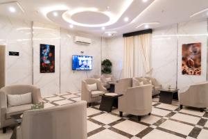 艾卜哈فندق رحيب للشقق المخدومة Rahib Suites的一间设有白色椅子和电视的等候室