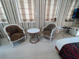 孟买Capital Hotel的一间设有两把椅子、一张桌子和一张床的房间
